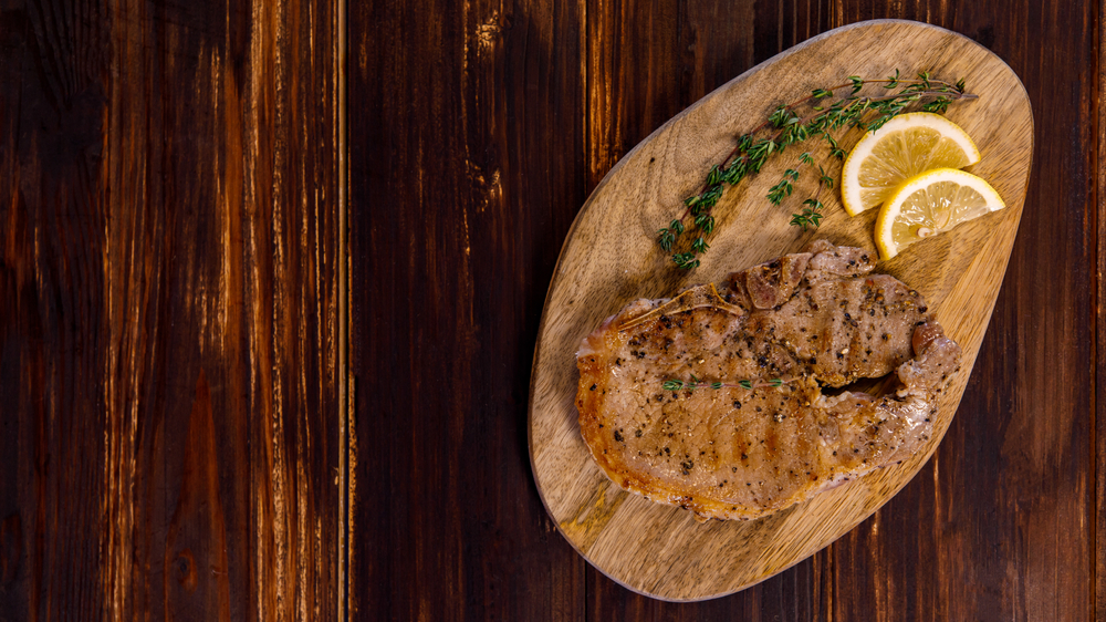 Pork,Steak,With,Lemon,And,Herbs,On,Wood,Plate,Taken