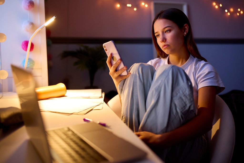 Worried Teenage Girl Sitting At Desk In Bedroom At Home, Einsamkeit